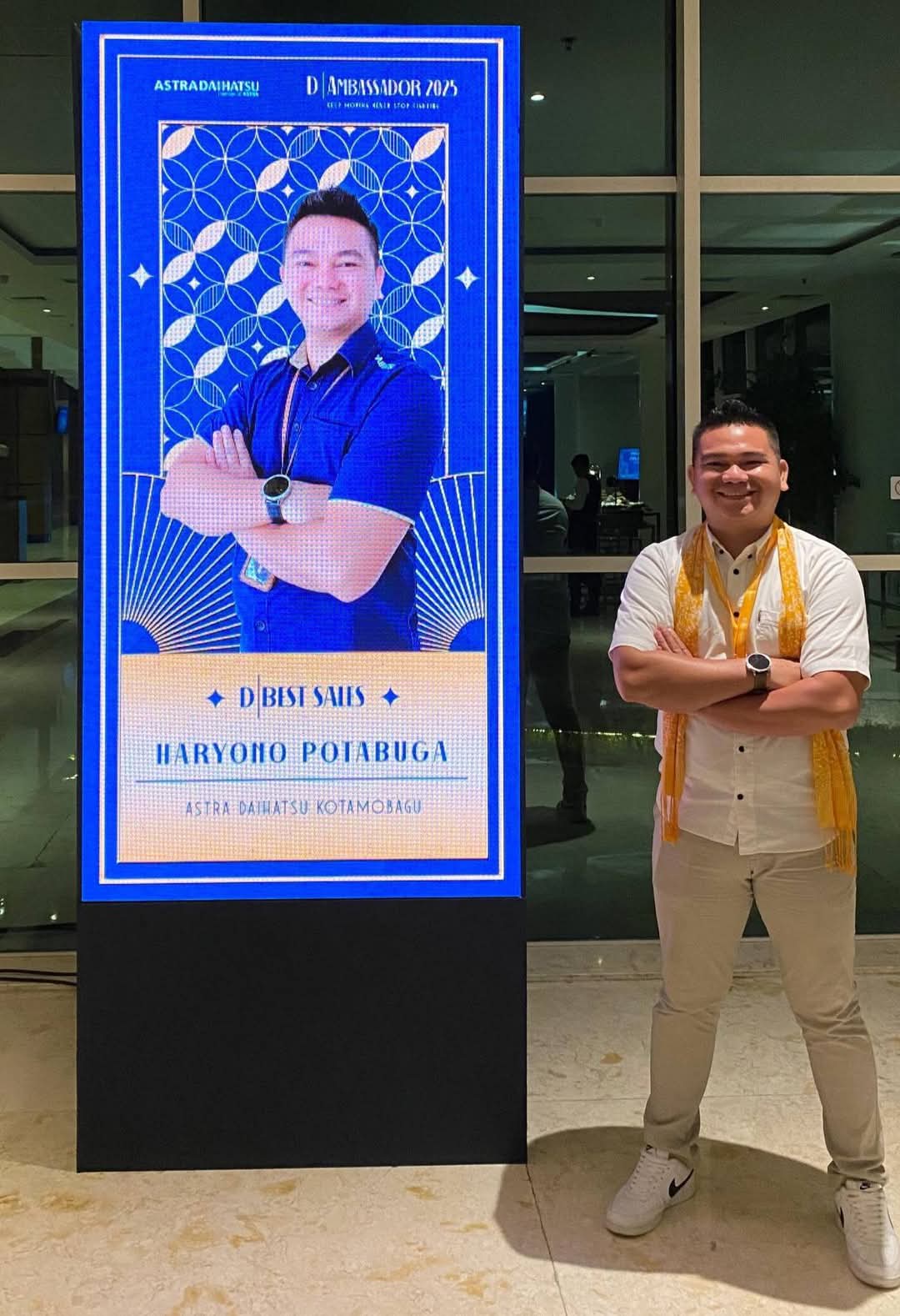 Ayi Potabuga berdiri di samping layar penghargaan Best Sales Daihatsu